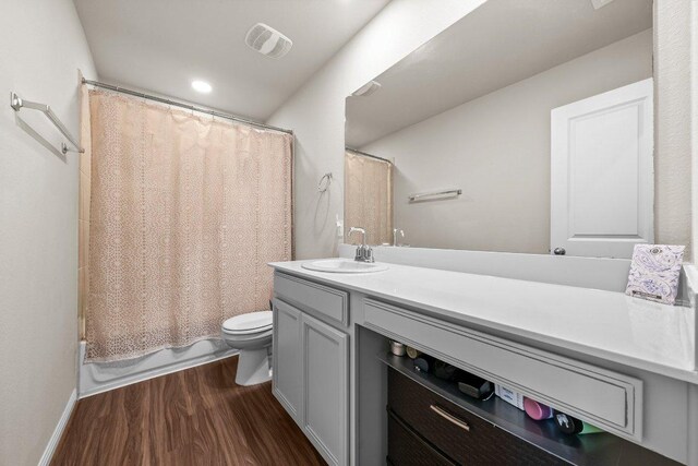 bathroom featuring vanity, toilet, shower / bath combo with shower curtain, wood finished floors, and visible vents