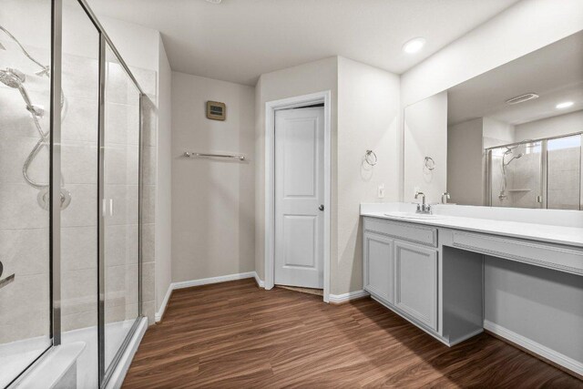 full bath featuring vanity, baseboards, a shower stall, and wood finished floors