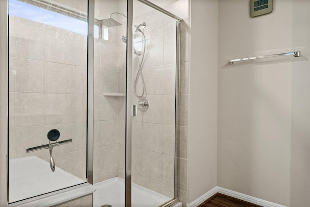 bathroom featuring baseboards, wood finished floors, and a stall shower