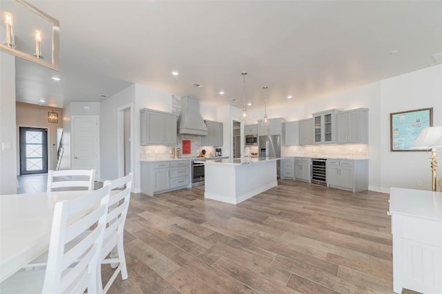 2228 Williams Lakeshore Dr, Kingsland, TX 78639 - kitchen with beverage cooler, appliances with stainless steel finishes, gray cabinetry, and custom range hood