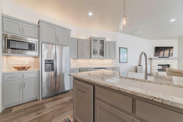 2228 Williams Lakeshore Dr, Kingsland, TX 78639 - kitchen featuring wood finished floors, a fireplace, a sink, gray cabinetry, and stainless steel appliances