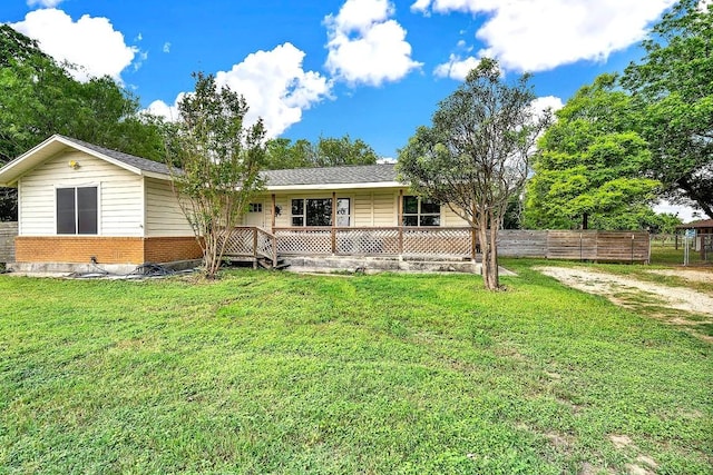 view of front of house with brick siding, a front lawn, fence, and covered porch