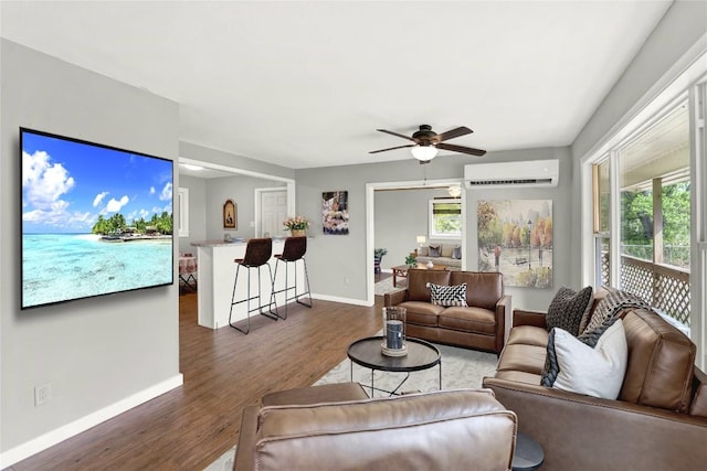 living area featuring baseboards, a wall mounted AC, wood finished floors, and ceiling fan