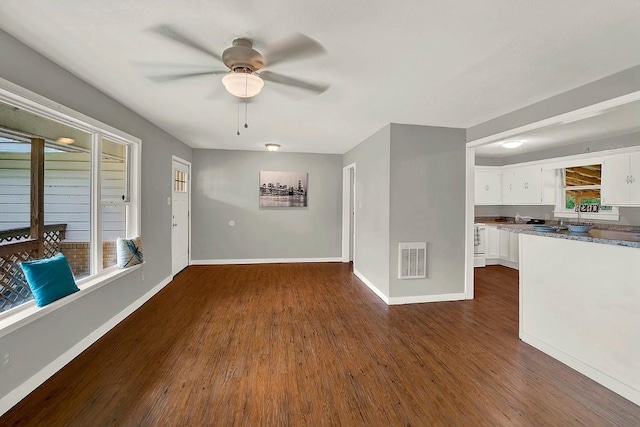 interior space with dark wood-style flooring, baseboards, visible vents, and a ceiling fan
