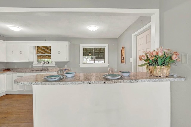 kitchen with light countertops, white cabinetry, a sink, and light wood-style floors