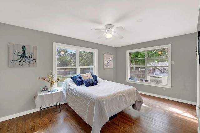 bedroom with baseboards, multiple windows, and wood finished floors