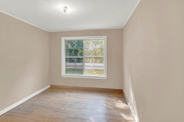 empty room with crown molding, baseboards, and wood finished floors