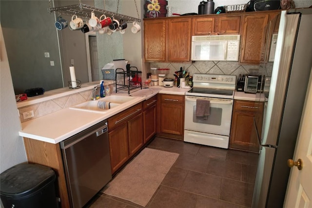 kitchen featuring a peninsula, light countertops, brown cabinets, tasteful backsplash, and stainless steel appliances
