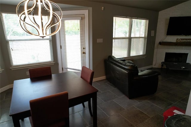 dining space with baseboards, lofted ceiling, a notable chandelier, and a fireplace