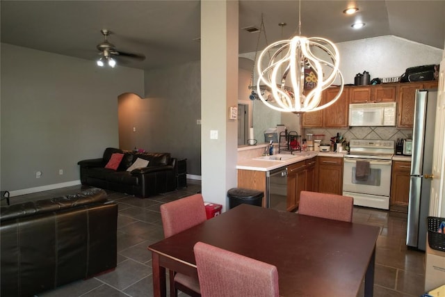 kitchen with ceiling fan with notable chandelier, dark tile patterned floors, stainless steel appliances, and light countertops