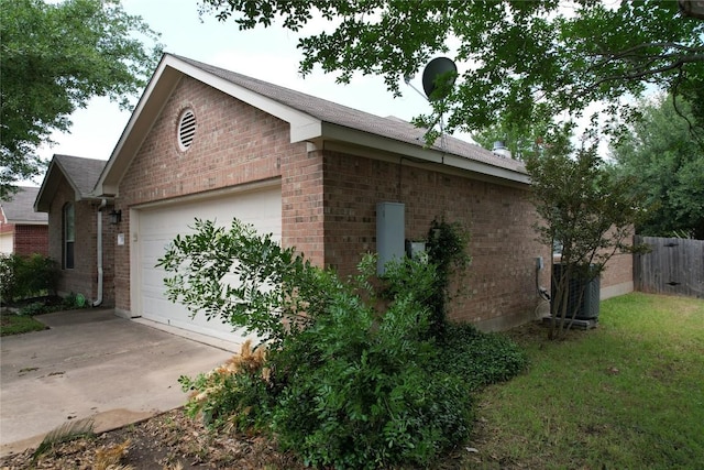 view of home's exterior with driveway, a garage, central air condition unit, brick siding, and fence
