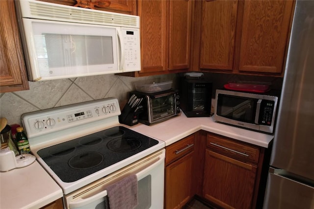 kitchen with brown cabinets, light countertops, stainless steel appliances, decorative backsplash, and a toaster