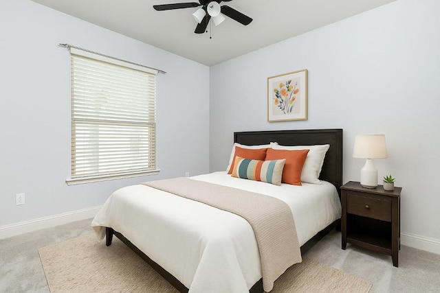 bedroom with light colored carpet, a ceiling fan, baseboards, and multiple windows