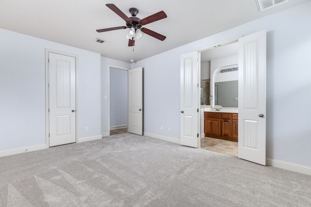 unfurnished bedroom featuring connected bathroom, baseboards, visible vents, and light carpet