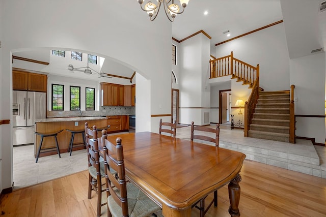 dining space with visible vents, ornamental molding, stairs, arched walkways, and ceiling fan with notable chandelier