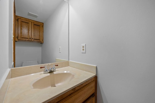 half bathroom featuring toilet, visible vents, and vanity