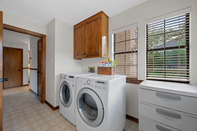 washroom with plenty of natural light, baseboards, cabinet space, and washing machine and dryer