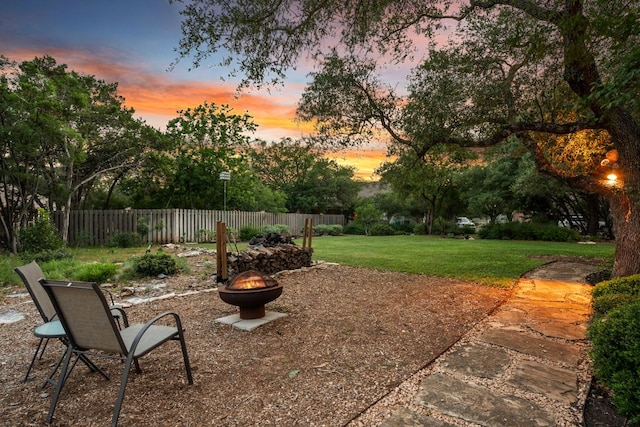 yard at dusk with a fire pit and fence