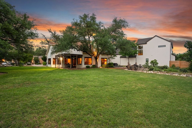 rear view of property featuring a lawn and stucco siding