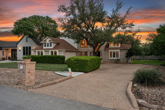 view of front of property featuring a lawn, fence, driveway, and a garage