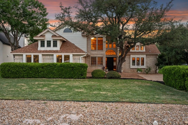 view of front facade featuring a lawn and a shingled roof