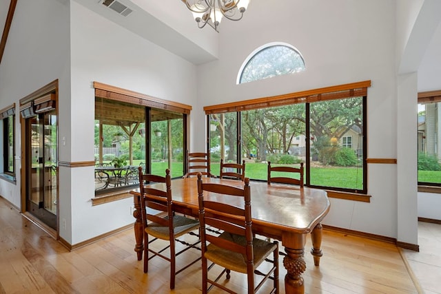 dining room featuring a notable chandelier, a high ceiling, visible vents, and light wood-style flooring