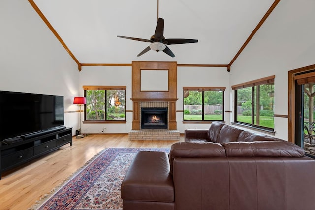 living area featuring crown molding, a brick fireplace, ceiling fan, and wood finished floors