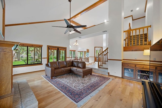 living area with wood finished floors, baseboards, a high ceiling, stairway, and ceiling fan with notable chandelier