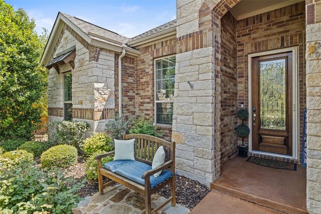5217 Cedro Elm Dr, Austin, TX 78738 - view of exterior entry featuring stone siding, a shingled roof, and brick siding