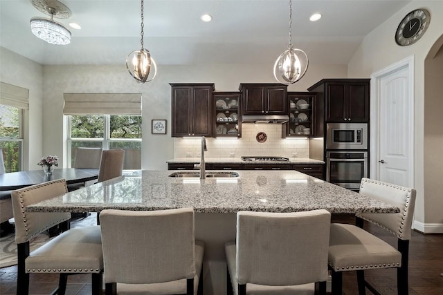 kitchen featuring decorative backsplash, glass insert cabinets, a chandelier, a sink, and appliances with stainless steel finishes
