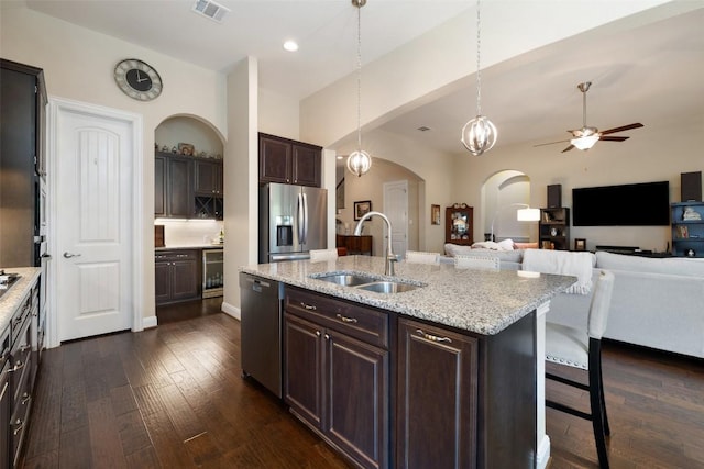 kitchen with visible vents, arched walkways, a sink, stainless steel appliances, and dark wood-type flooring