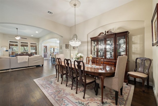 dining room with visible vents, dark wood-type flooring, recessed lighting, arched walkways, and ceiling fan with notable chandelier