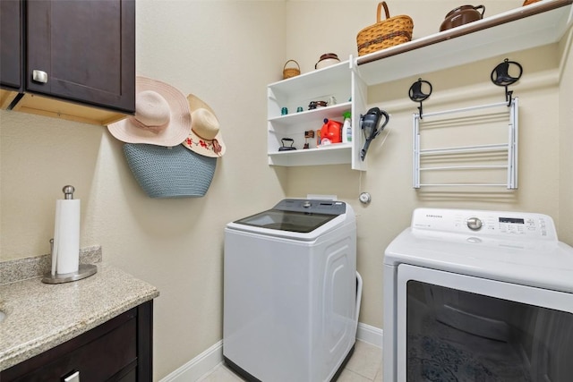 laundry area with washing machine and clothes dryer, light tile patterned flooring, baseboards, and cabinet space