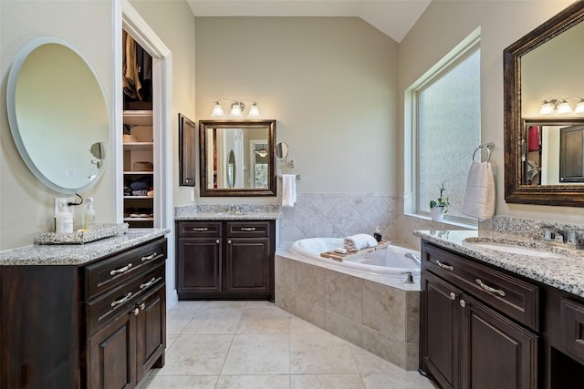 bathroom with a garden tub, two vanities, a sink, tile patterned floors, and lofted ceiling