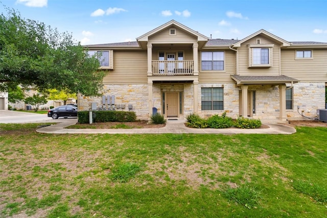 view of property featuring a front lawn, a balcony, stone siding, and cooling unit