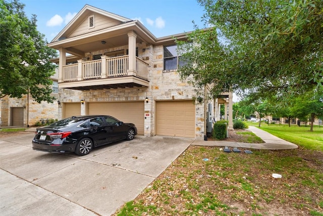 townhome / multi-family property featuring an attached garage, driveway, a balcony, and stone siding