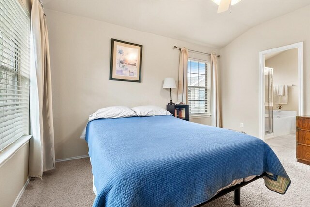 carpeted bedroom featuring baseboards, ensuite bath, and vaulted ceiling