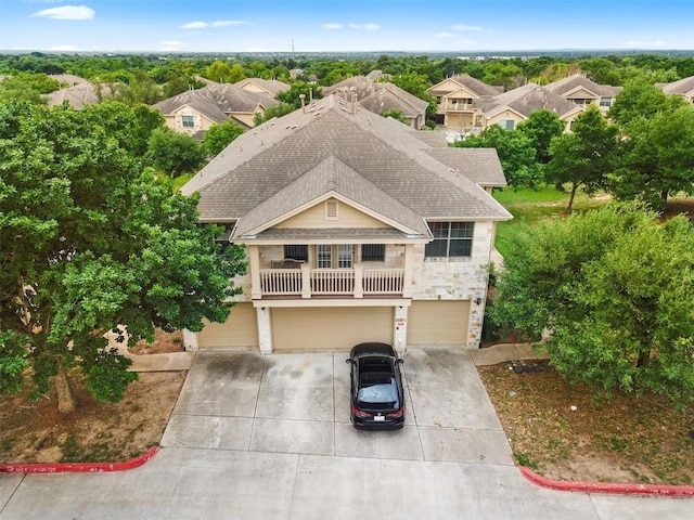 view of front facade featuring stone siding, an attached garage, driveway, and roof with shingles