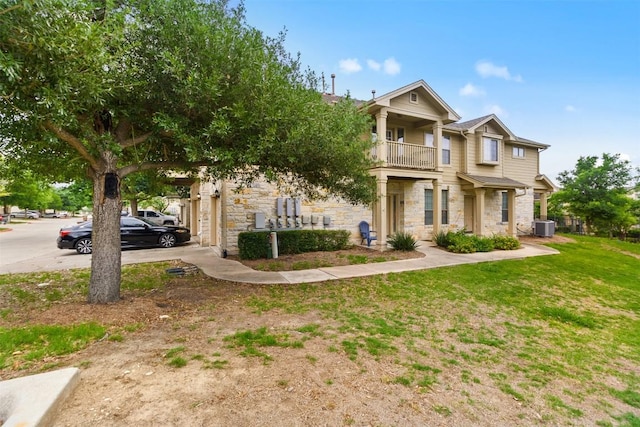 craftsman-style home featuring a front yard, central AC, a balcony, and stone siding