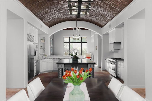dining space with brick ceiling, arched walkways, baseboards, and an inviting chandelier