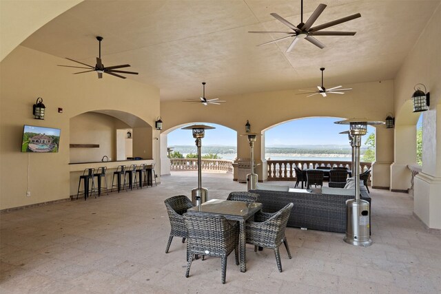 view of patio / terrace featuring outdoor dining area, a water view, ceiling fan, and a bar