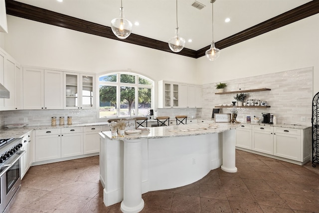 kitchen with crown molding, decorative backsplash, high end stainless steel range, and visible vents