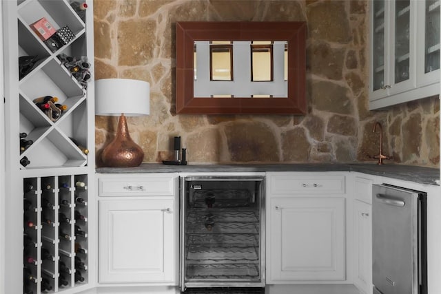 bar with beverage cooler, decorative backsplash, and wet bar
