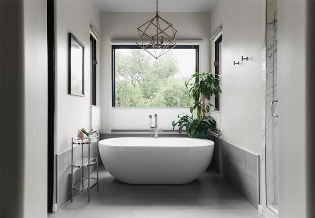 bathroom featuring a freestanding tub, a shower stall, tile patterned floors, and a chandelier