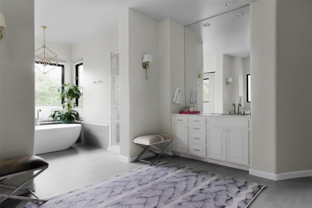 full bath featuring vanity, a freestanding tub, baseboards, recessed lighting, and a stall shower