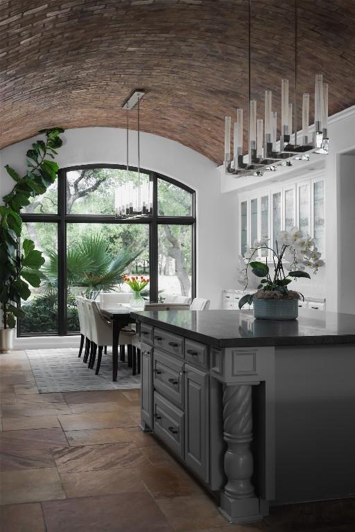 bar with a chandelier, pendant lighting, stone finish floor, and lofted ceiling
