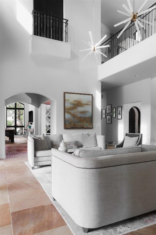 living room featuring arched walkways, a ceiling fan, and a high ceiling