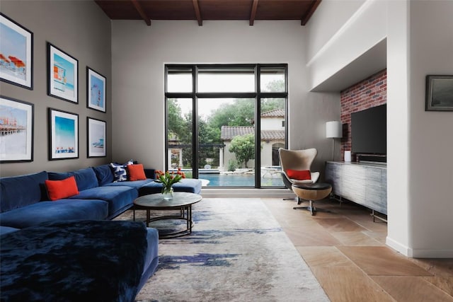 living area featuring baseboards, stone finish floor, wooden ceiling, and beamed ceiling