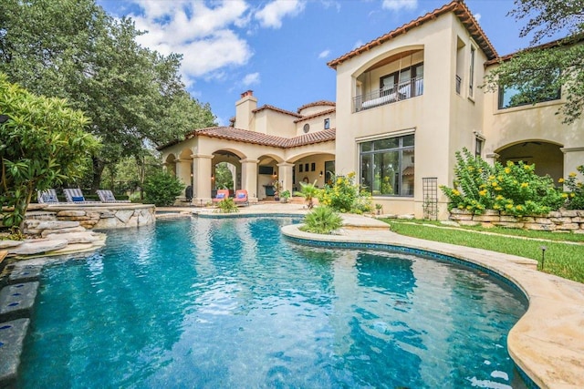 201 Costa Bella Dr, Austin, TX 78734 - rear view of property featuring stucco siding, a balcony, a tile roof, a pool with connected hot tub, and a chimney