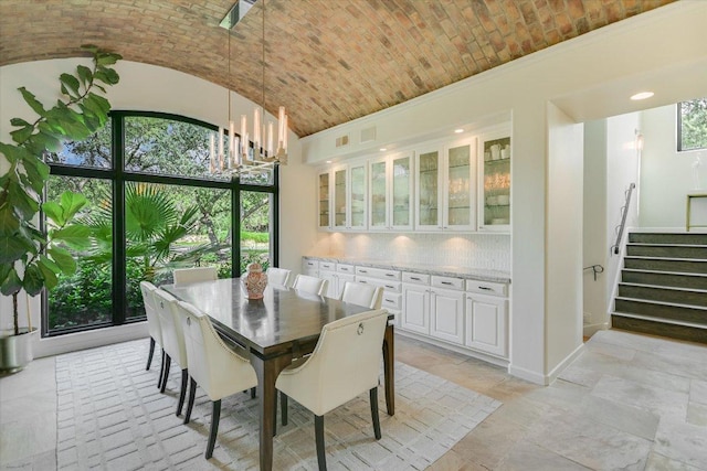 201 Costa Bella Dr, Austin, TX 78734 - dining room featuring healthy amount of natural light, brick ceiling, stairs, lofted ceiling, and stone tile floors